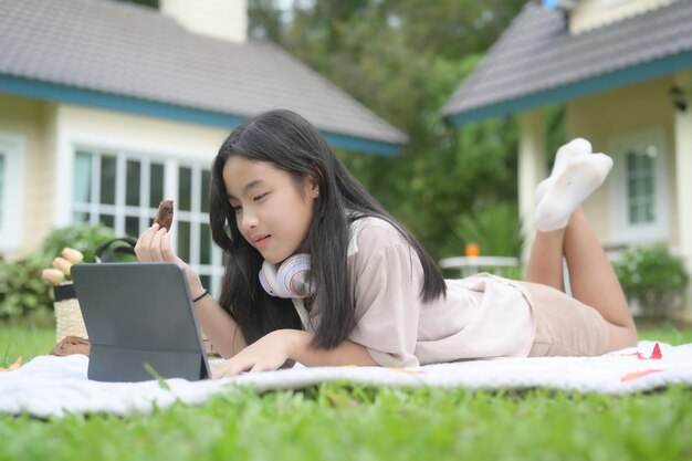 Jonge vrouw die op groen gras ligt en computertablet gebruikt