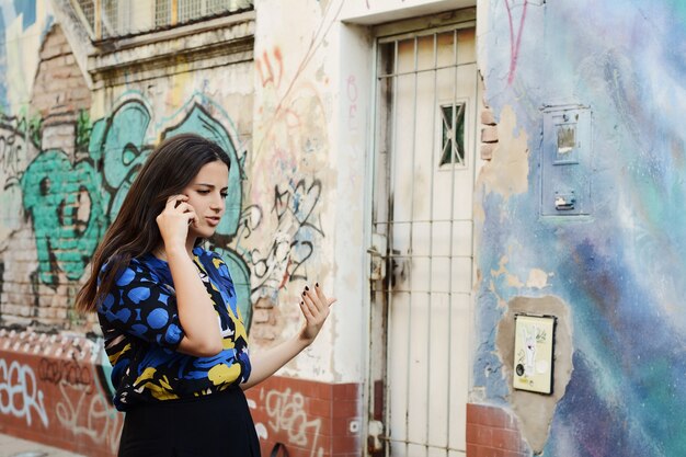 Jonge vrouw die op haar mobiele telefoon spreekt.