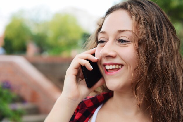 Foto jonge vrouw die op haar mobiele telefoon spreekt.