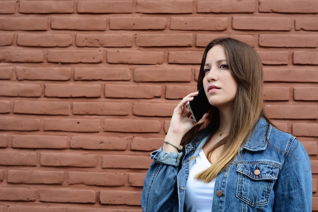 Jonge vrouw die op haar mobiele telefoon spreekt.