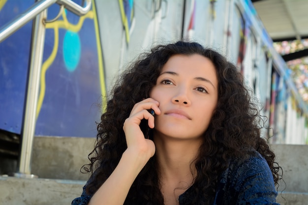 Jonge vrouw die op haar mobiele telefoon spreekt.