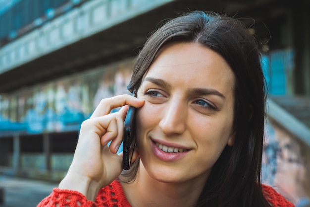 Jonge vrouw die op haar mobiele telefoon spreekt.