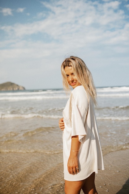Jonge vrouw die op het strand staat tegen de lucht.