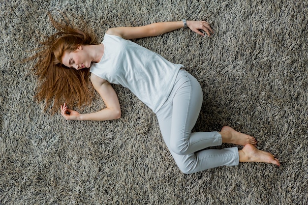 Jonge vrouw die op het tapijt legt