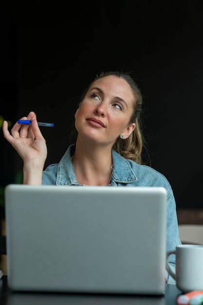 Jonge vrouw die op kantoor werkt in een denkende bui Rechtenvrije Stockafbeeldingen