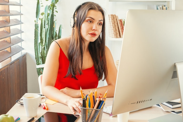 Jonge vrouw die op kantoor werkt met behulp van een computer die aan een bureau zit