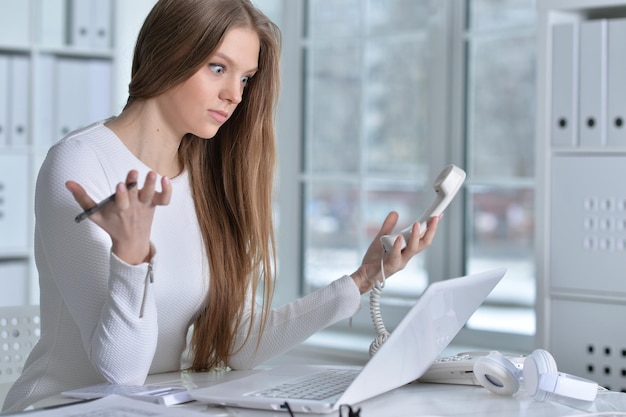 Jonge vrouw die op kantoor werkt met behulp van laptop