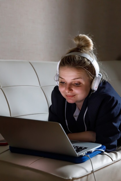 Jonge vrouw die op laptopcomputer werkt terwijl ze in de woonkamer zit.