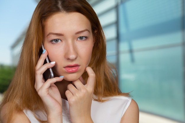 Jonge vrouw die op mobiele telefoon spreekt