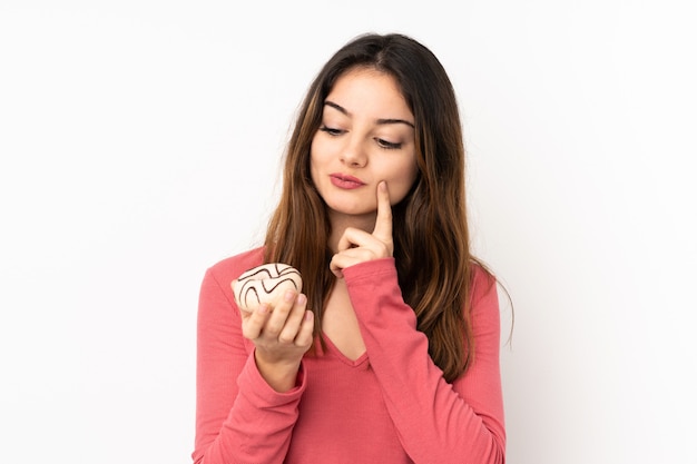 Jonge vrouw die op roze een doughnut houdt