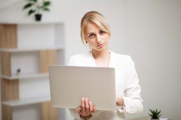 Jonge vrouw die op schoot in het bureau werkt.