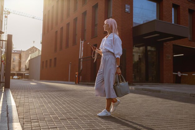 Jonge vrouw die op straat staat en een mobiele telefoon vasthoudt