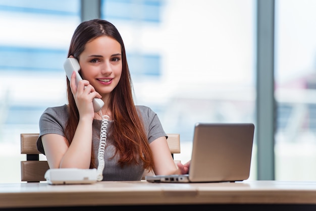 Foto jonge vrouw die op telefoon in bureau spreekt