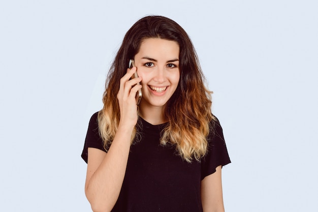 Jonge vrouw die op telefoon in een studio spreekt