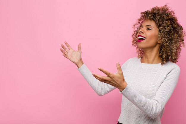 Jonge vrouw die opera uitvoert of bij een concert of show zingt, die romantisch, artistiek en hartstochtelijk voelt tegen roze muur