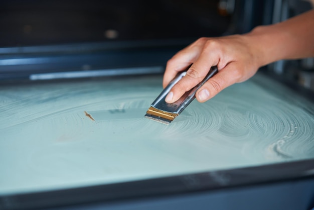 Jonge vrouw die oven in de keuken schoonmaakt