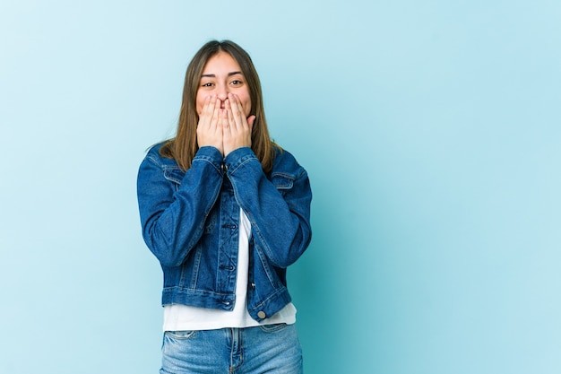 Jonge vrouw die over iets lacht, mond bedekt met handen