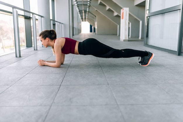 Jonge vrouw die planktraining doet die binnen opleidt.