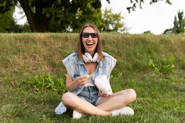 Jonge vrouw die popcorn eet terwijl het zitten op het gras