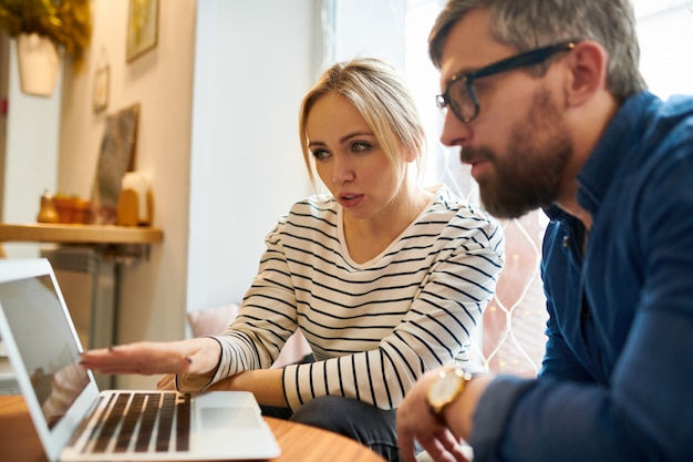 Jonge vrouw die presentatie maakt aan haar collega terwijl het richten op online gegevens in laptop op vergadering