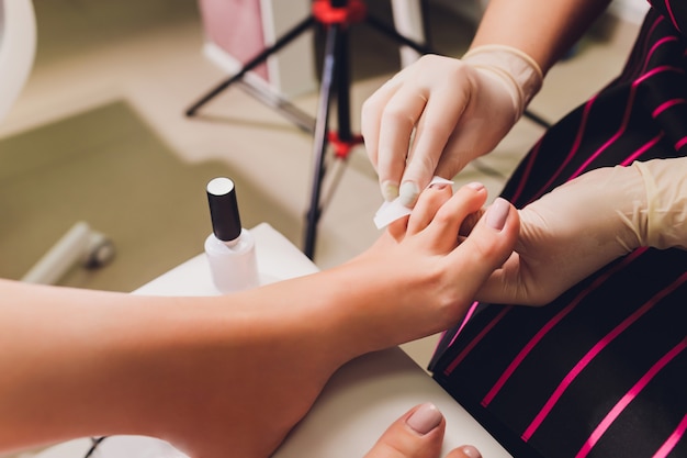 Foto jonge vrouw die professionele pedicure in schoonheidssalon, close-up krijgt.