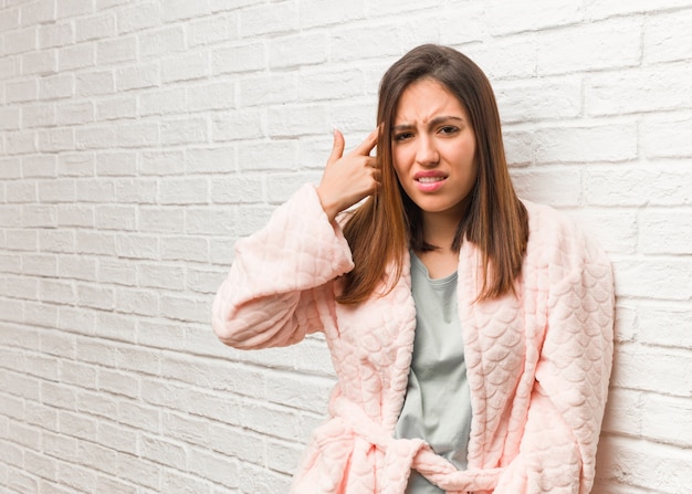 Jonge vrouw die pyjama draagt die een teleurstellingsgebaar met vinger doet