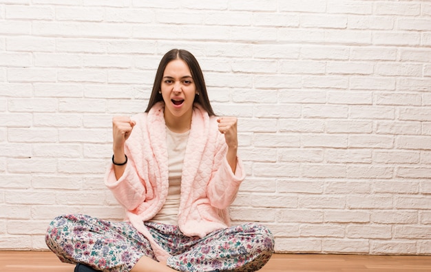 Jonge vrouw die pyjama draagt die zeer boos en agressief gilt