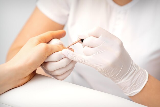 Jonge vrouw die roze of beige nagellak ontvangt in een schoonheidssalon.