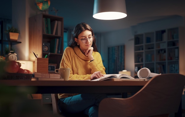 Jonge vrouw die's avonds laat studeert.