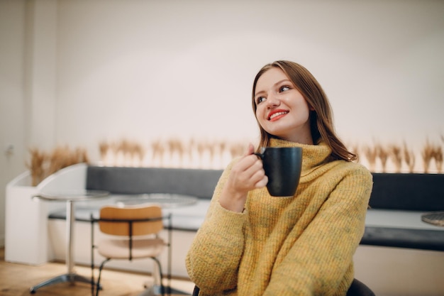 Jonge vrouw die 's ochtends koffie drinkt in café