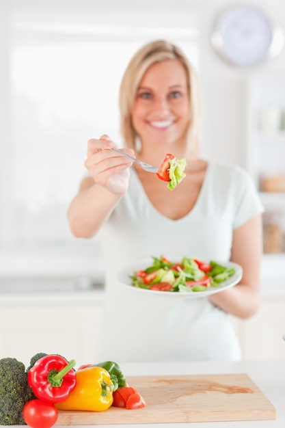 Jonge vrouw die salade aanbiedt