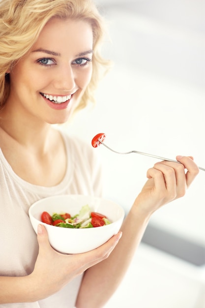 jonge vrouw die salade eet in de keuken