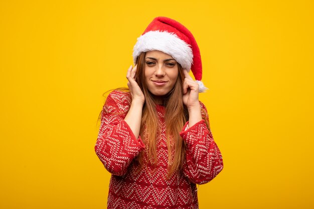 Jonge vrouw die santahoed draagt ​​die oren behandelt met handen