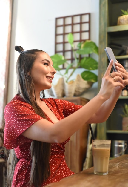 Jonge vrouw die selfie neemt in een coffeeshop