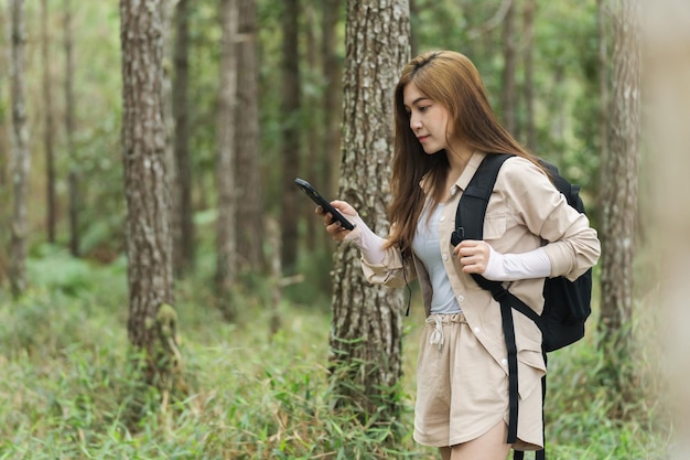 Jonge vrouw die smartphone gebruikt om te navigeren door elektronische kaart in het bos