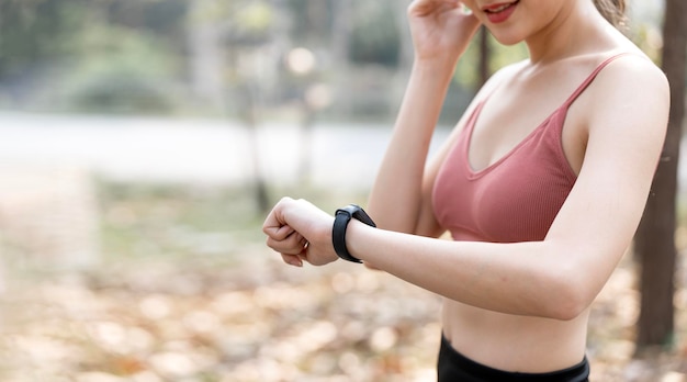 Jonge vrouw die smartwatch gebruikt, controleert Activity Tracker tijdens buitenoefeningen