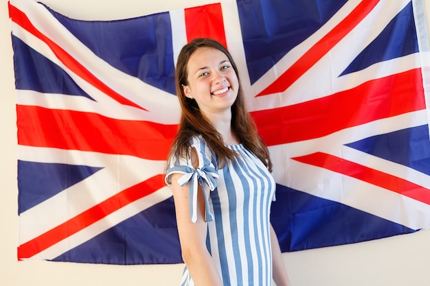 Jonge vrouw die tegen de vlag van het Verenigd Koninkrijk staat