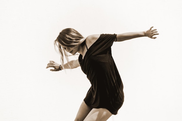 Jonge vrouw die tegen een witte achtergrond danst