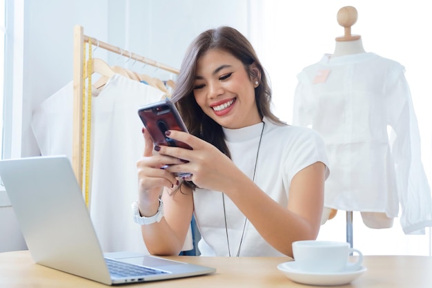 Jonge vrouw die telefoon gebruikt terwijl ze op tafel zit