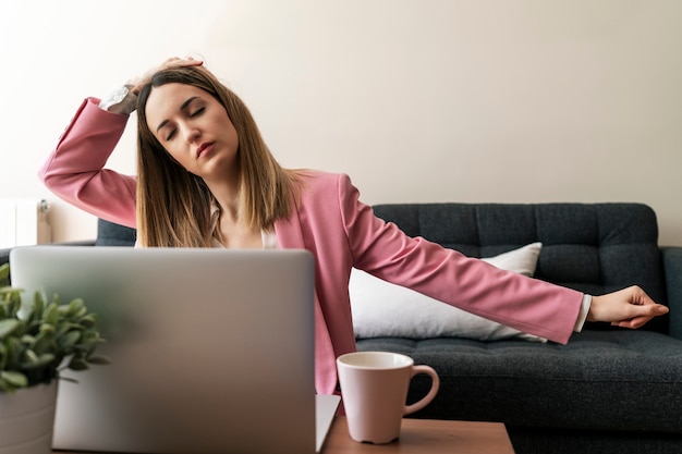 Jonge vrouw die terwijl zij van huis werkt uitrekt zich. Blijf thuis, werk vanuit huis concept.