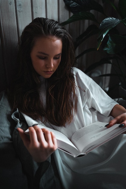 Jonge vrouw die thuis een boek leest