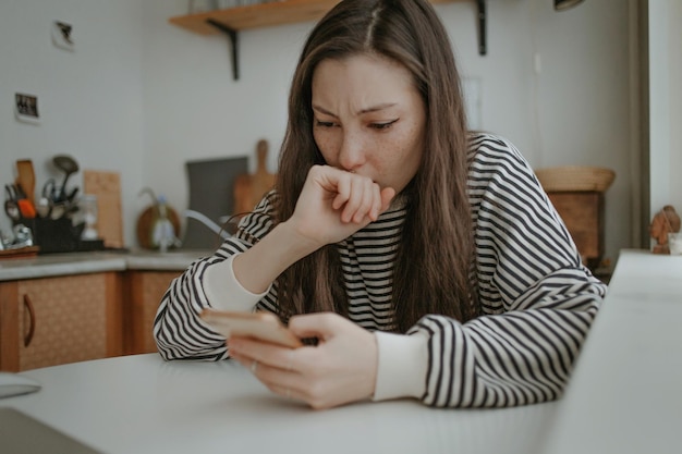 Foto jonge vrouw die thuis een mobiele telefoon gebruikt