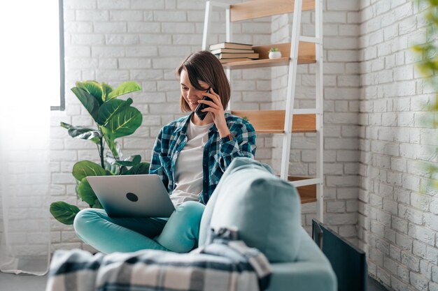 Foto jonge vrouw die thuis een mobiele telefoon gebruikt