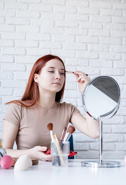 Jonge vrouw die thuis make-up gebruikt met oogschaduw