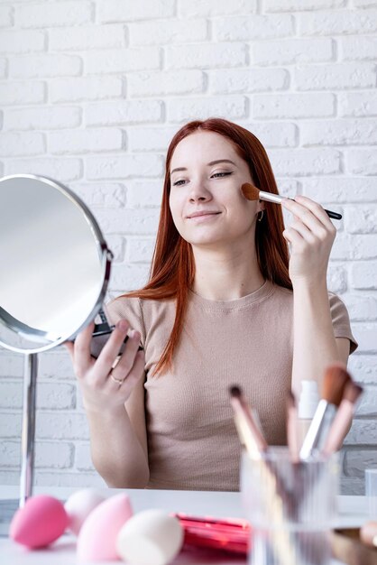 Jonge vrouw die thuis make-up gebruikt met oogschaduw