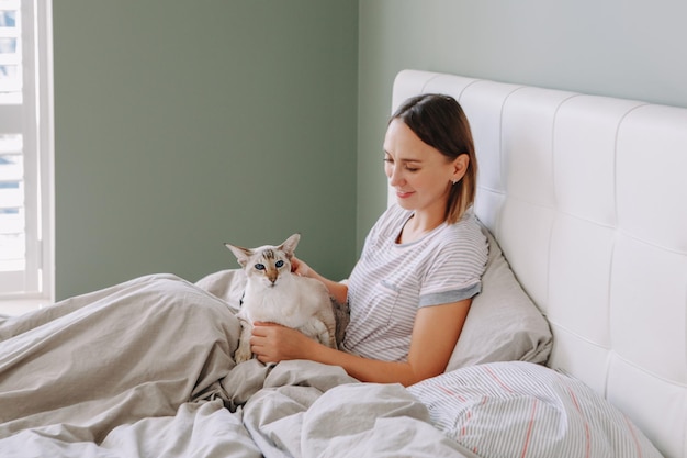 Jonge vrouw die thuis op bed zit.