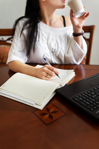 Jonge vrouw die thuis op een laptop werkt aan tafel online leren op pc e-learning Online werken op afstand