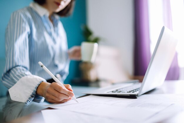 Jonge vrouw die thuis schrijft en werkt met Notebook Freelancer werkt en maakt aantekeningen