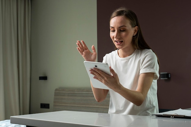 Foto jonge vrouw die thuis werkt met een digitale tablet en blij is met het succes
