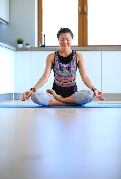 Jonge vrouw die thuis yoga doet in de lotuspositie Yoga Woman Lifestyle